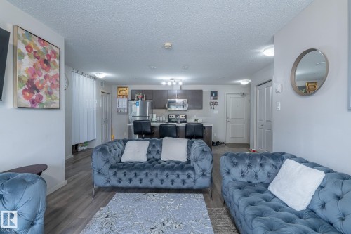 Open-concept living space with wood-finish flooring, recessed lighting, and a modern kitchen - 107 142 Ebbers Boulevard, Edmonton, AB 