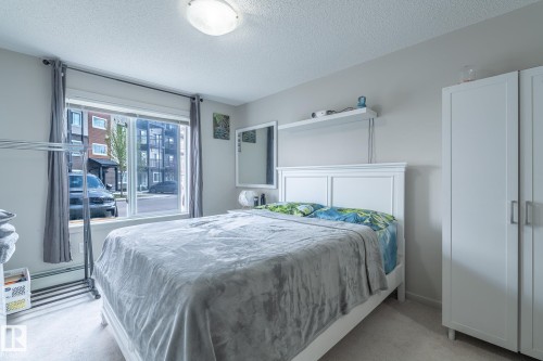 Bedroom featuring a large window, light-colored walls, and carpet flooring - 107 142 Ebbers Boulevard, Edmonton, AB 