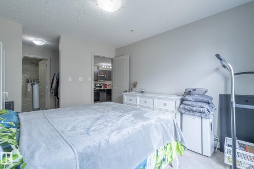 Neutral wall color palette, textured ceiling, flush mount ceiling light fixture, white interior doors, and carpeted flooring - 107 142 Ebbers Boulevard, Edmonton, AB 
