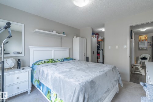 Bedroom featuring a white paneled headboard and a matching two-drawer nightstand - 107 142 Ebbers Boulevard, Edmonton, AB 
