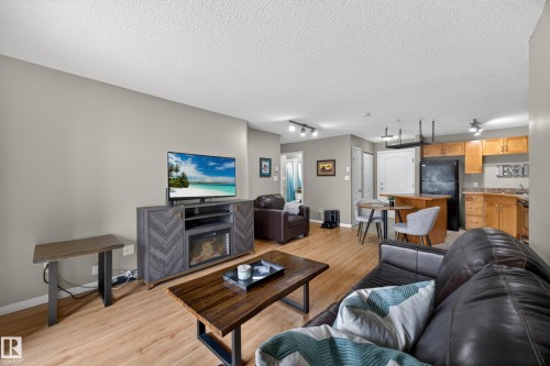 Open-concept living space featuring wood-finish flooring, light grey painted walls, and a textured ceiling - 111 3425 19, Edmonton, AB 