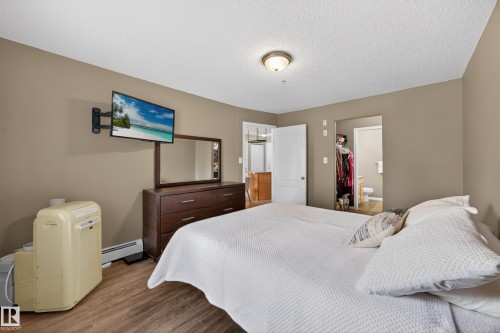 Bedroom featuring wood-finish flooring, neutral wall paint, and a semi-flush ceiling light fixture - 111 3425 19, Edmonton, AB 