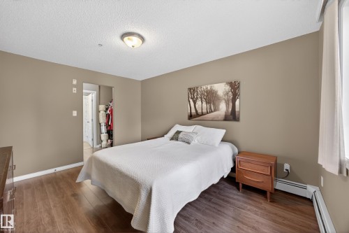 Bedroom featuring wood-finish flooring, neutral wall paint, and a textured ceiling - 111 3425 19, Edmonton, AB 