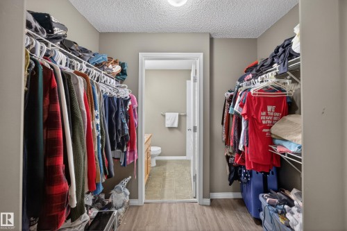 Walk-in closet featuring wire shelving, hanging rods, and wood-finish flooring - 111 3425 19, Edmonton, AB 