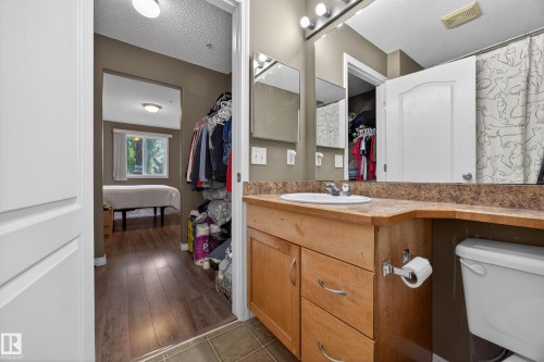Bathroom vanity with a built-in sink, wood-finish cabinetry, and a countertop with integrated backsplash - 111 3425 19, Edmonton, AB 