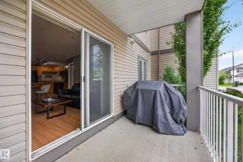 Private concrete patio with white railing and a sliding glass door entry to the interior - 111 3425 19, Edmonton, AB 