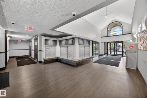 Lobby with wood-finish flooring, vaulted ceiling, and an arched transom window - 111 3425 19, Edmonton, AB 