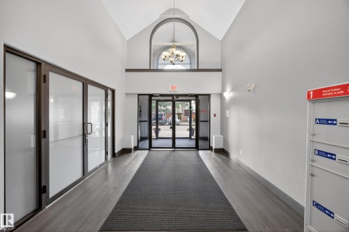 Spacious entry hallway featuring vaulted ceilings, wood-finish flooring, and frosted glass paneled doors - 111 3425 19, Edmonton, AB 