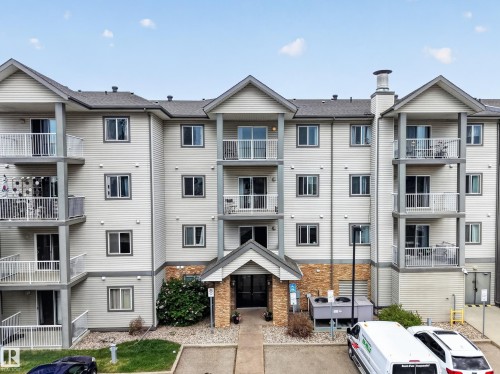Multi-story residential building featuring light-colored siding and a contrasting gray roof - 111 3425 19, Edmonton, AB 