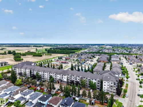 Expansive aerial perspective showcasing a multi-story residential building with light-colored siding and dark-pitched roofs - 111 3425 19, Edmonton, AB 