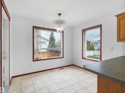 Bright room featuring two large windows with dark wood trim, tile flooring, a decorative crystal chandelier, and a wood-finish counter - 