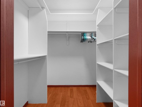 Walk-in closet featuring white shelving units, hanging rods, and wood-finish flooring - 2832 36B Avenue, Edmonton, AB - Indoor With Storage