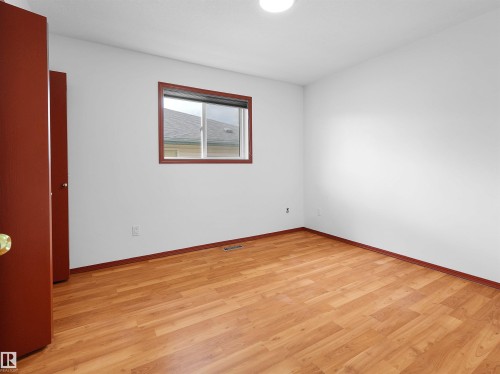 Room featuring wood-finish flooring, white walls, and a window with red trim - 2832 36B Avenue, Edmonton, AB - Indoor Photo Showing Other Room