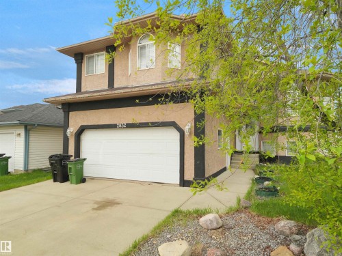 Two-story stucco exterior featuring a white garage door, concrete driveway, and a paved walkway leading to the front entry - 2832 36B Avenue, Edmonton, AB - Outdoor