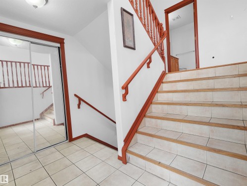 Entryway with a tiled floor and a staircase featuring wood-finish treads and a matching wood railing - 2832 36B Avenue, Edmonton, AB - Indoor Photo Showing Other Room