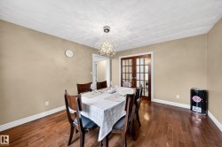 Dining area featuring wood-finish flooring, neutral wall tones, and white trim - 