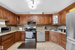 U-shaped kitchen featuring wood cabinetry, light-toned granite countertops, and a mosaic tile backsplash - 