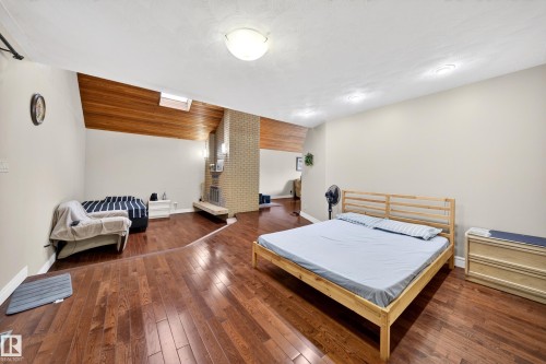 Interior space featuring wood-finish flooring, a brick fireplace with a hearth, and a vaulted wood-paneled ceiling with an integrated skylight - 34 Grand Meadow Crescent, Edmonton, AB 