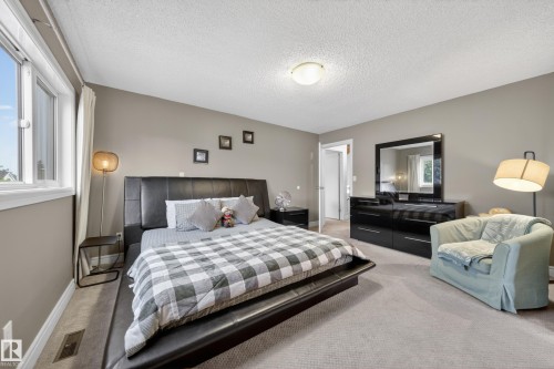 Carpeted bedroom featuring neutral wall tones, a window with white trim, and a ceiling-mounted light fixture - 34 Grand Meadow Crescent, Edmonton, AB 