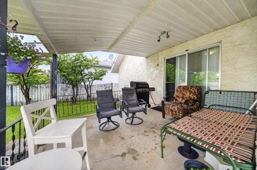 Covered patio space featuring a concrete slab, textured stucco exterior, and sliding glass doors - 34 Grand Meadow Crescent, Edmonton, AB 
