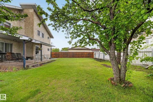 Expansive green space featuring a mature tree, a covered patio, and a stucco exterior - 34 Grand Meadow Crescent, Edmonton, AB 