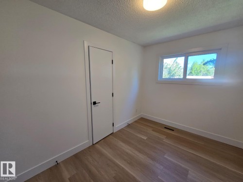 Room featuring wood-finish flooring, a contemporary white door with matte black hardware, and a window with white trim - 18526 86A Avenue, Edmonton, AB - Indoor Photo Showing Other Room