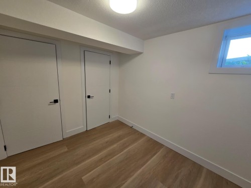 Room featuring wood-finish flooring, white walls, and two white doors with matte black hardware - 18526 86A Avenue, Edmonton, AB - Indoor Photo Showing Other Room