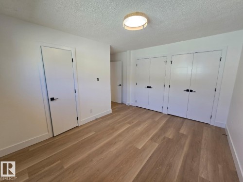 Spacious room featuring wood-finish flooring, crisp white walls, and a contemporary flush-mount ceiling light - 18526 86A Avenue, Edmonton, AB - Indoor Photo Showing Other Room