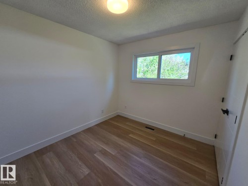 Bright interior space featuring wood-finish flooring, white baseboards, and a large window with white trim - 18526 86A Avenue, Edmonton, AB - Indoor Photo Showing Other Room