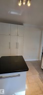 Kitchen island with a black countertop and a white base featuring an integrated handle - 