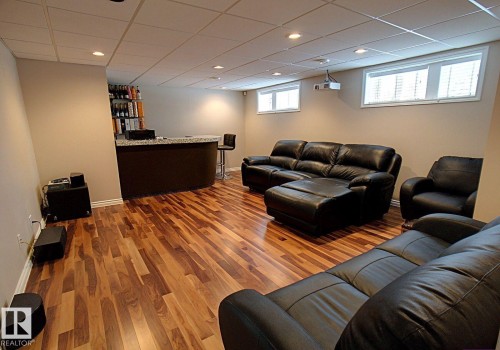 Spacious recreation room featuring wood-finish flooring, recessed lighting, and a built-in bar with a stone-finish countertop - 6704 93 Street, Edmonton, AB 