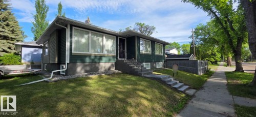 Dark green siding with white trim, featuring multiple large windows - 6704 93 Street, Edmonton, AB 