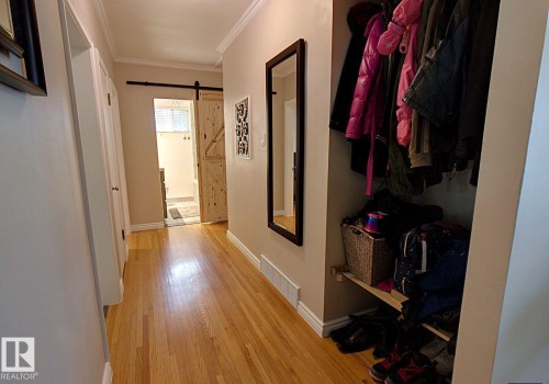 Hallway featuring wood-finish flooring, white baseboards, and crown molding - 6704 93 Street, Edmonton, AB 