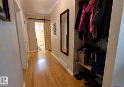 Hallway featuring wood-finish flooring, white baseboards, and crown molding - 