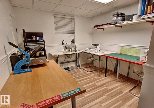 Craft room featuring wood-finish flooring, white walls, and a drop ceiling - 6704 93 Street, Edmonton, AB 