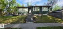 Split-level residence featuring dark green siding, white trim, and a prominent front entry staircase - 6704 93 Street, Edmonton, AB 