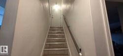 Tiled staircase with white risers and a metal handrail - 