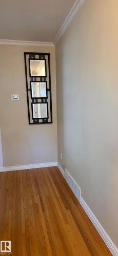 Honey-toned wood-finish flooring with white baseboards and crown molding - 6704 93 Street, Edmonton, AB 