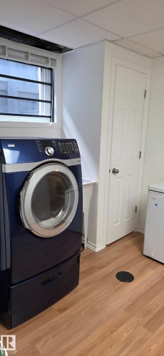 Dedicated laundry area featuring wood-finish flooring and a utility sink - 6704 93 Street, Edmonton, AB 