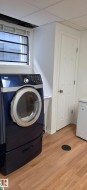Dedicated laundry area featuring wood-finish flooring and a utility sink - 