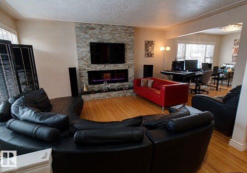 Living area featuring a floor-to-ceiling stacked stone accent wall with an integrated linear fireplace - 6704 93 Street, Edmonton, AB 