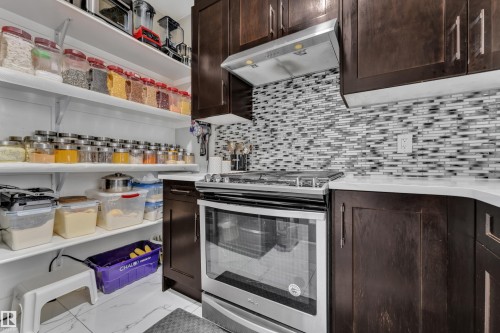 Kitchen featuring dark wood-finish cabinetry, white countertops, and a full stainless steel range with overhead ventilation - 2419 15 Avenue, Edmonton, AB 