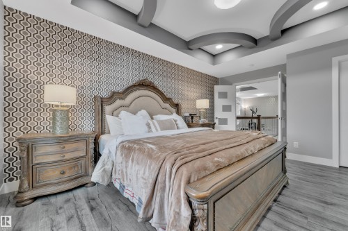 Recessed lighting and a tray ceiling with accent arches highlight this space, featuring wood-finish flooring - 2419 15 Avenue, Edmonton, AB 