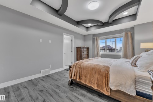 Bedroom featuring a decorative tray ceiling with recessed lighting, wood-finish flooring, a double window, and light gray wall paint - 2419 15 Avenue, Edmonton, AB 