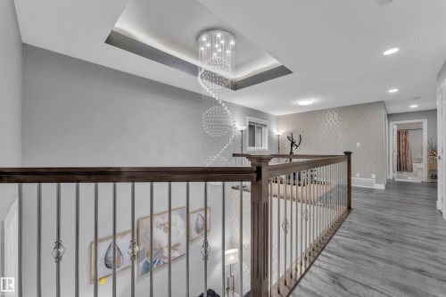 Upper-level landing featuring a contemporary chandelier, recessed ceiling lighting, wood-finish flooring, and a decorative accent wall - 2419 15 Avenue, Edmonton, AB 