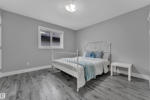 Spacious room featuring wood-finish flooring, a contemporary window, and neutral wall tones - 2419 15 Avenue, Edmonton, AB 
