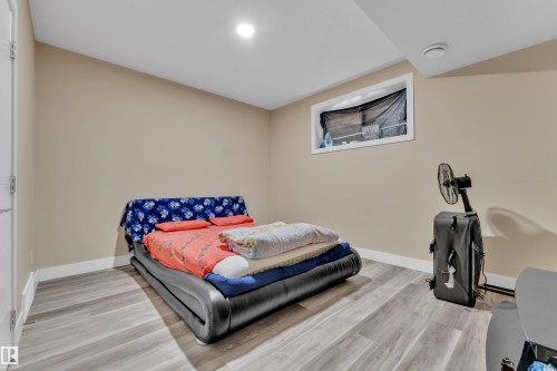 Spacious room with wood-finish flooring, neutral-toned walls, and white baseboards - 2419 15 Avenue, Edmonton, AB 
