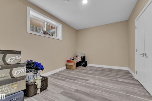 Spacious room featuring wood-finish flooring, neutral-toned walls, and a white-trimmed window - 2419 15 Avenue, Edmonton, AB 