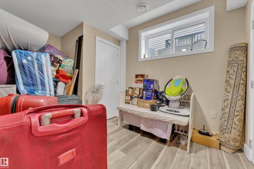 Basement space featuring light wood-finish flooring, a white window frame, and a white interior door - 2419 15 Avenue, Edmonton, AB 