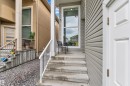 Entryway featuring concrete steps with white railings, a full-length window, and light gray horizontal siding - 2419 15 Avenue, Edmonton, AB 